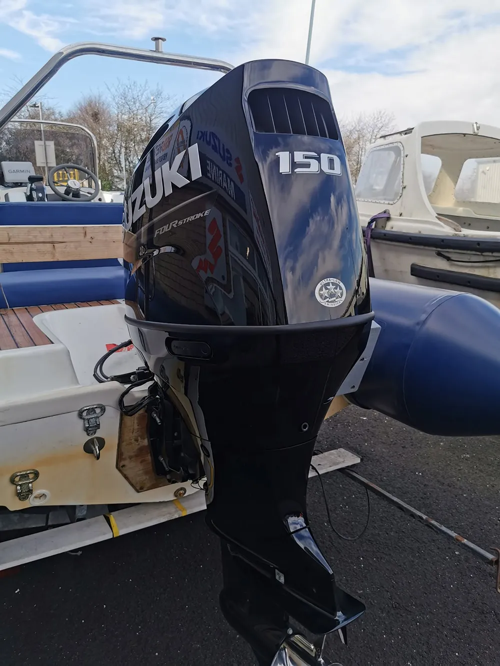 An outboard newly fitted to the transom of a rigid inflatable boat on a trailer in the yard