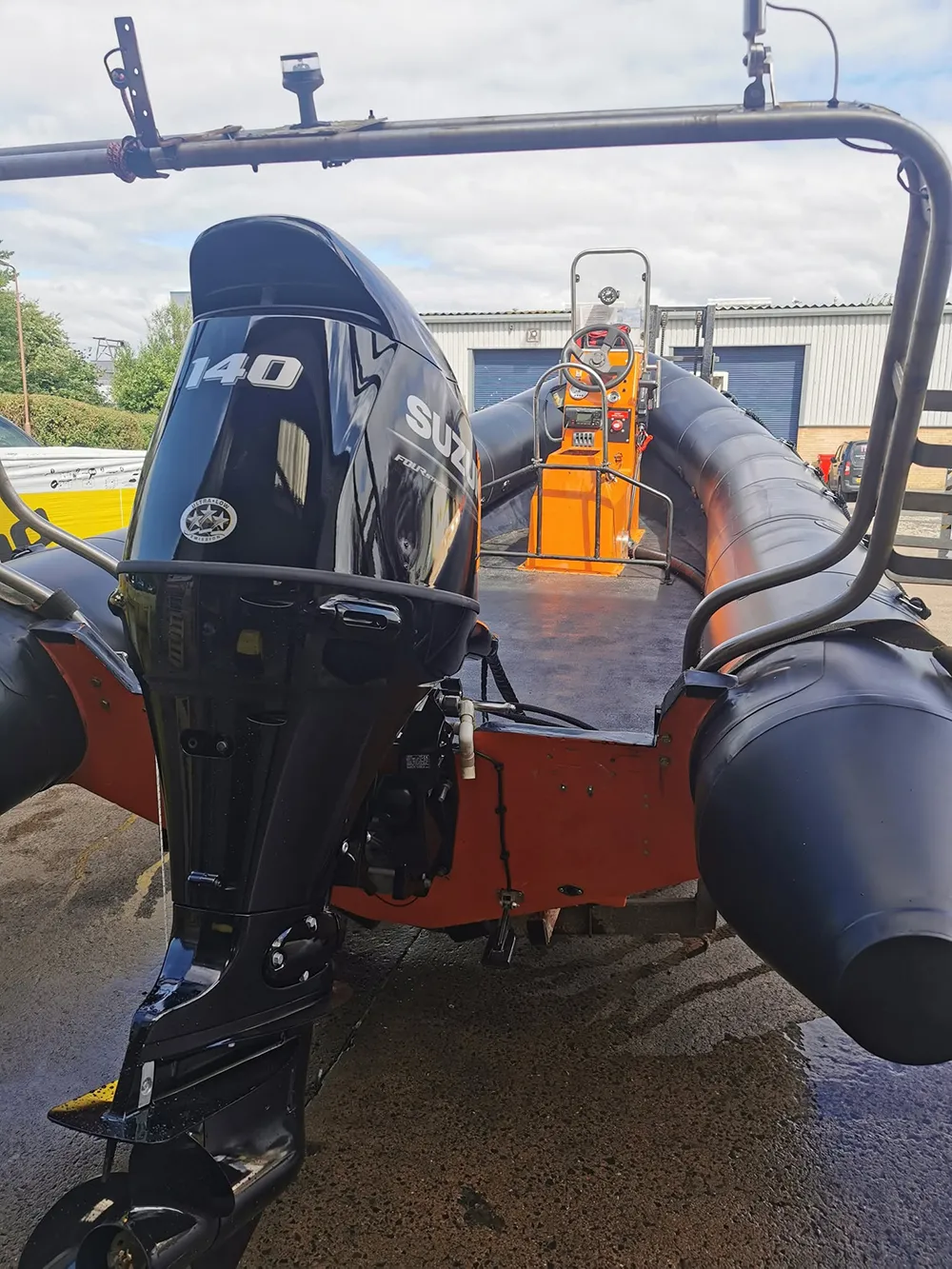 Suzuki DF140 outboard fitted to a black and orange RIB outside Ferry Marine's Livingston workshop