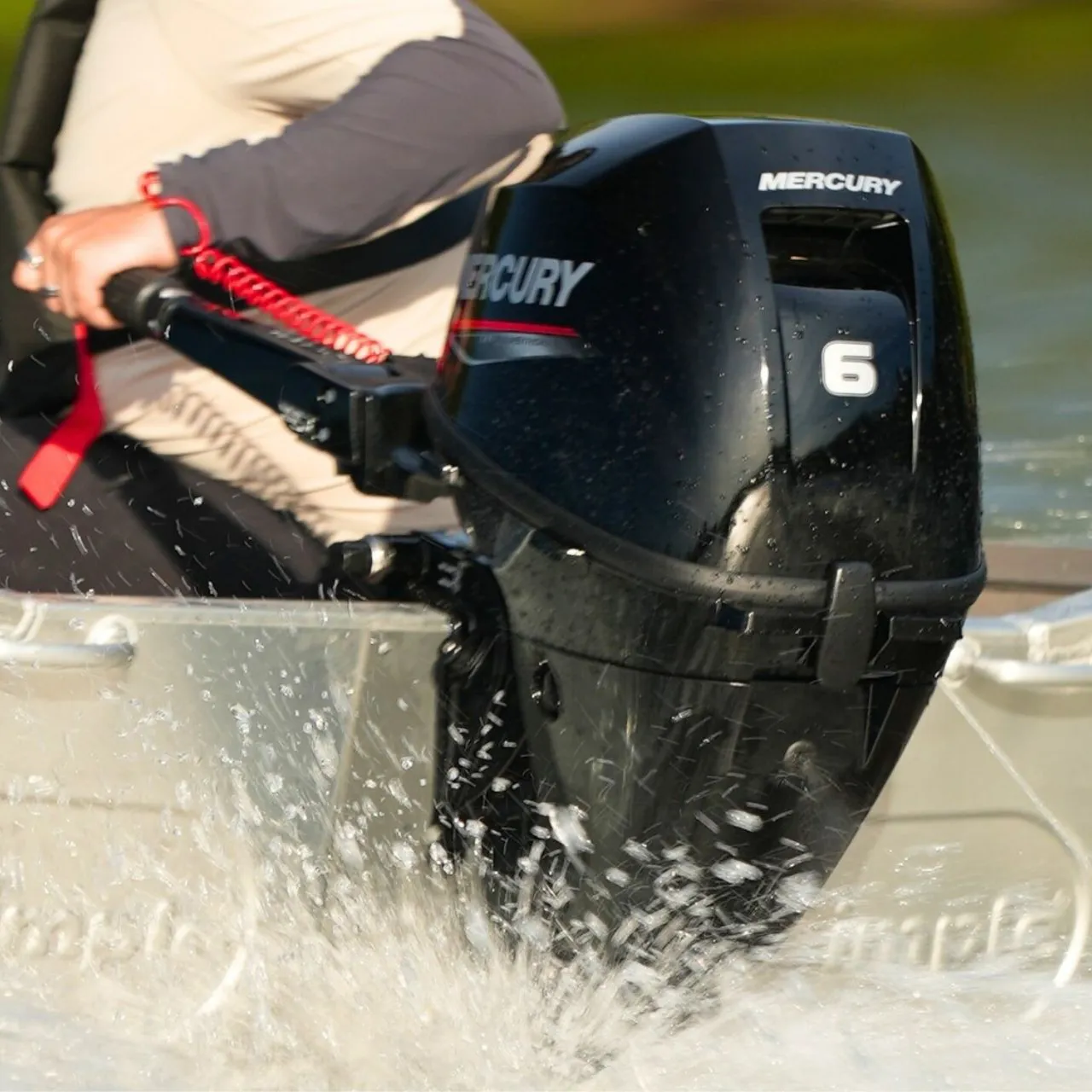 Mercury 6hp outboard on the transom of an aluminium boat, tiller-steered and throwing spray