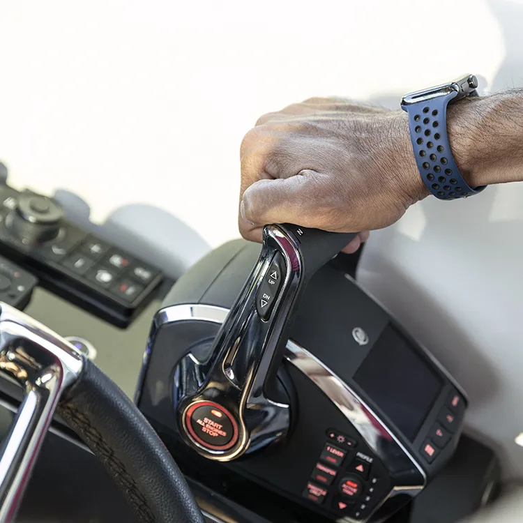 Hand on a Mercury Digital Throttle & Shift control lever at a boat's helm, beside the engine start/stop button
