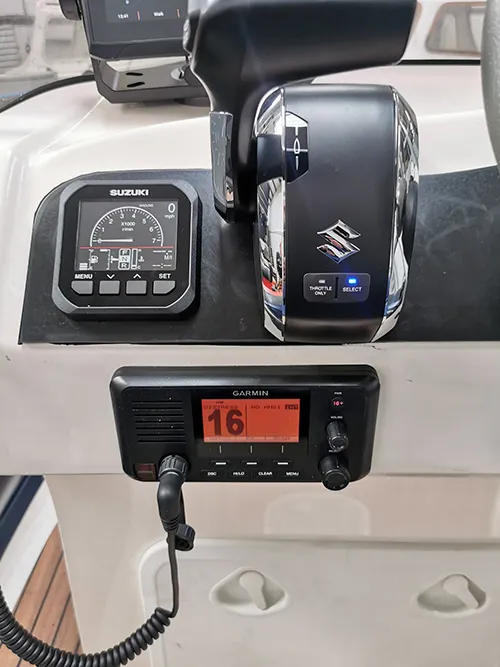 Engine display, throttle and VHF at the helm Digital engine display and electronic throttle on a boat dashboard, with a fixed VHF radio mounted below