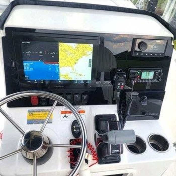 After: custom acrylic dashboard panel The same boat console fitted with a custom gloss-black acrylic dashboard panel holding a large chartplotter, VHF radio, stereo and a row of switches